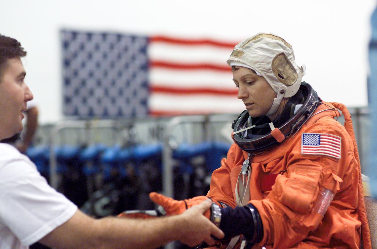 JSC2004-E-41381 (17 September 2004) --- Astronaut Eileen M. Collins, STS-114 commander, dons a training version of the shuttle launch and entry suit, prior to the start of a mission training session in the Neutral Buoyancy Laboratory (NBL) near Johnson Space Center (JSC). United Space Alliance (USA) suit technician Mike Thompson assisted Collins.