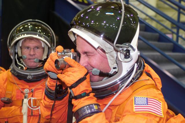 JSC2004-E-42288 (24 September 2004) --- Astronaut Stephen K. Robinson, STS-114 mission specialist, uses a still camera prior to the start of a mission training session in the Space Vehicle Mockup Facility at Johnson Space Center (JSC). Astronaut Andrew S. W. Thomas, mission specialist, looks on. Robinson and Thomas are wearing training versions of the shuttle launch and entry suit.
