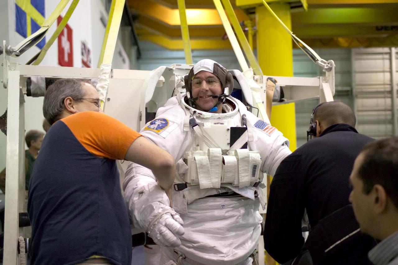 JSC2005-E-02827 (26 January 2005) --- Astronaut Stephen K. Robinson, STS-114 mission specialist, dons a training version of the Extravehicular Mobility Unit (EMU) spacesuit prior to being submerged in the waters of the Neutral Buoyancy Laboratory (NBL) near Johnson Space Center. Suit technicians assisted Robinson.