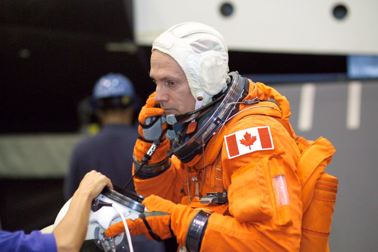 JSC2005-E-13822 (4 April 2005) --- Astronaut Steven G. MacLean, STS-115 mission specialist representing the Canadian Space Agency, dons a training version of the shuttle launch and entry suit prior to the start of an emergency egress training session in the Space Vehicle Mockup Facility at the Johnson Space Center.