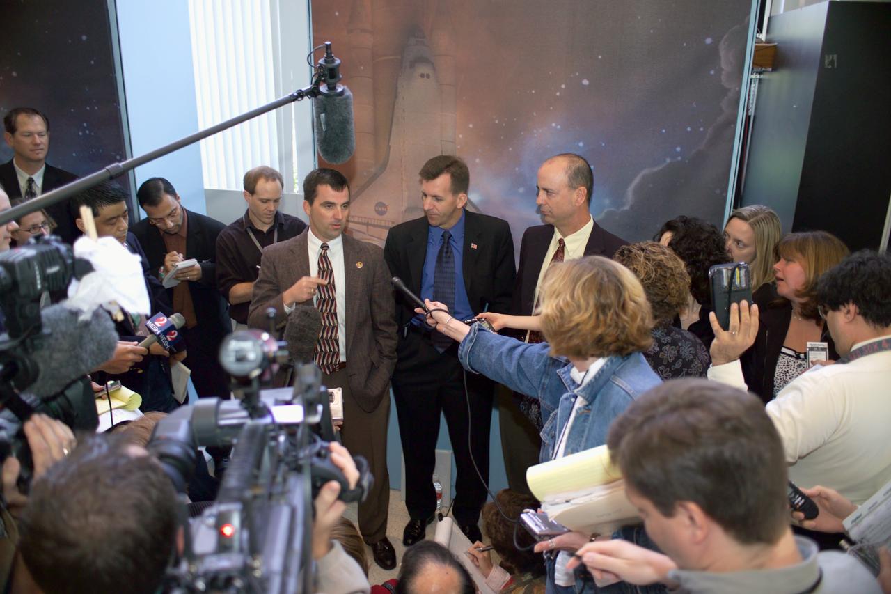 JSC2005-E-14182 (7 April 2005) --- Paul Hill (left center), STS-114 Lead Shuttle Flight Director; LeRoy Cain, Ascent/Entry Flight Director; and Mark Ferring, Lead ISS Flight Director, speak with various news media representatives following an STS-114 preflight press briefing in the Teague Auditorium at the Johnson Space Center (JSC).