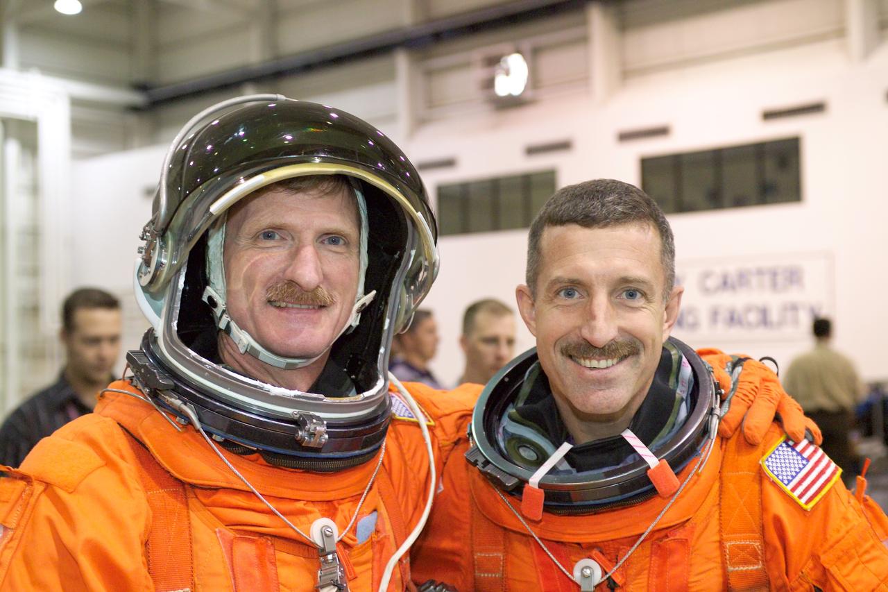 JSC2005-E-19190 (11 May 2005) --- Astronauts Joseph R. (Joe) Tanner (left) and Daniel C. Burbank, both STS-115 mission specialists, pose for a photo as they await the start of a water survival training session in the Neutral Buoyancy Laboratory (NBL) near Johnson Space Center. Tanner and Burbank are wearing training versions of the shuttle launch and entry suit.