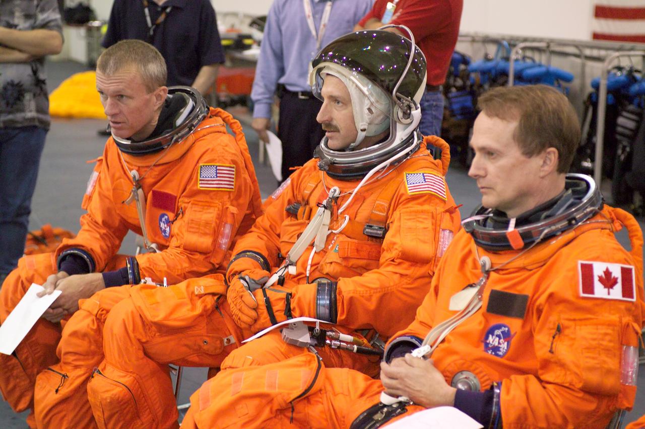 JSC2005-E-19203 (11 May 2005) --- Astronauts Brent W. Jett Jr. (left), STS-115 commander; Daniel C. Burbank, mission specialist; and Steven G. MacLean, mission specialist representing the Canadian Space Agency, attired in training versions of the shuttle launch and entry suit, observe fellow crewmembers during an emergency egress training session in the Neutral Buoyancy Laboratory (NBL) near Johnson Space Center.