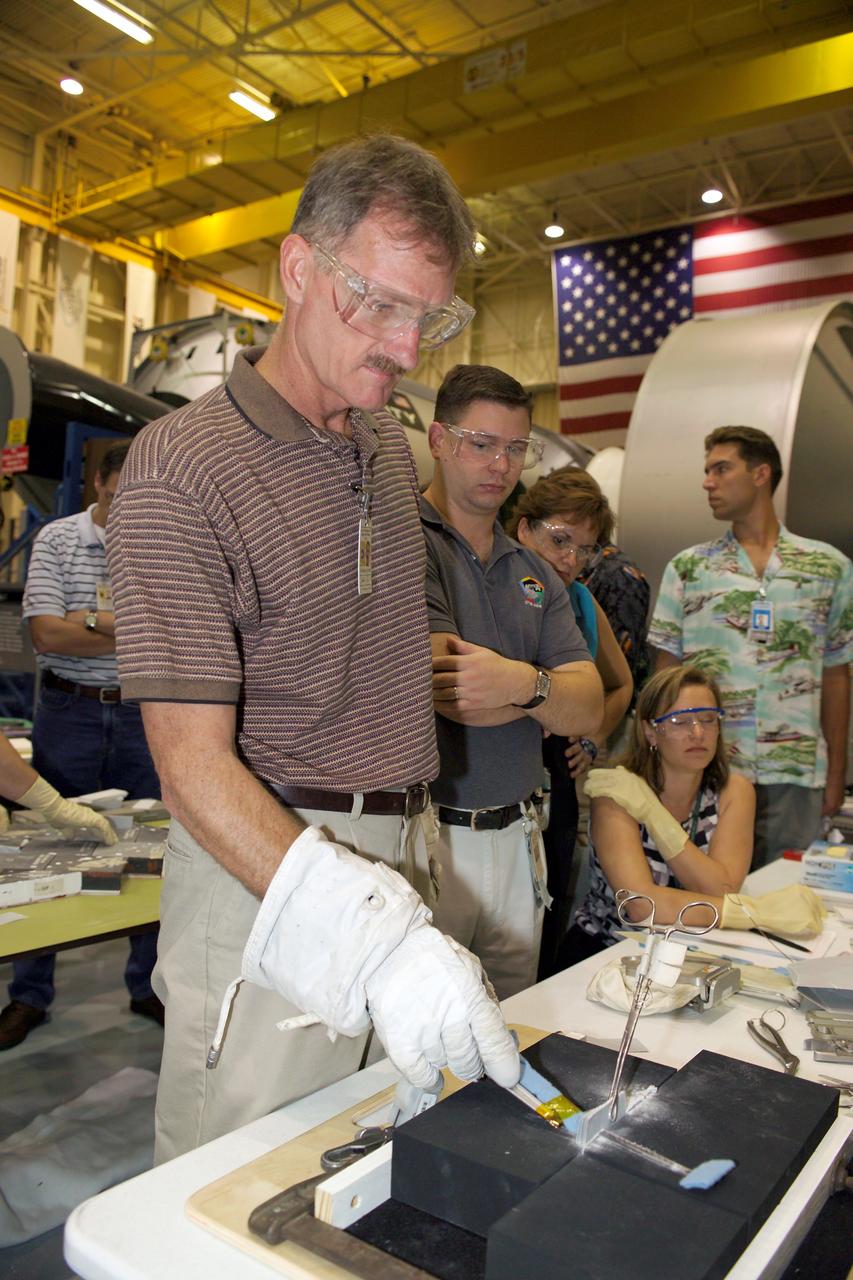 JSC2005-E-30915 (31 July 2005) --- NASA astronaut Joe Tanner (foreground) joins other astronauts and engineers at the Johnson Space Center to practice techniques to eliminate or trim protruding gap fillers that Astronauts Noguchi and Robinson will use during their spacewalk. The ceramic coated-fabric gap fillers are used to protect against hot gas from seeping into gaps between the Shuttle’s protective tiles. Photo credit: NASA/James Blair