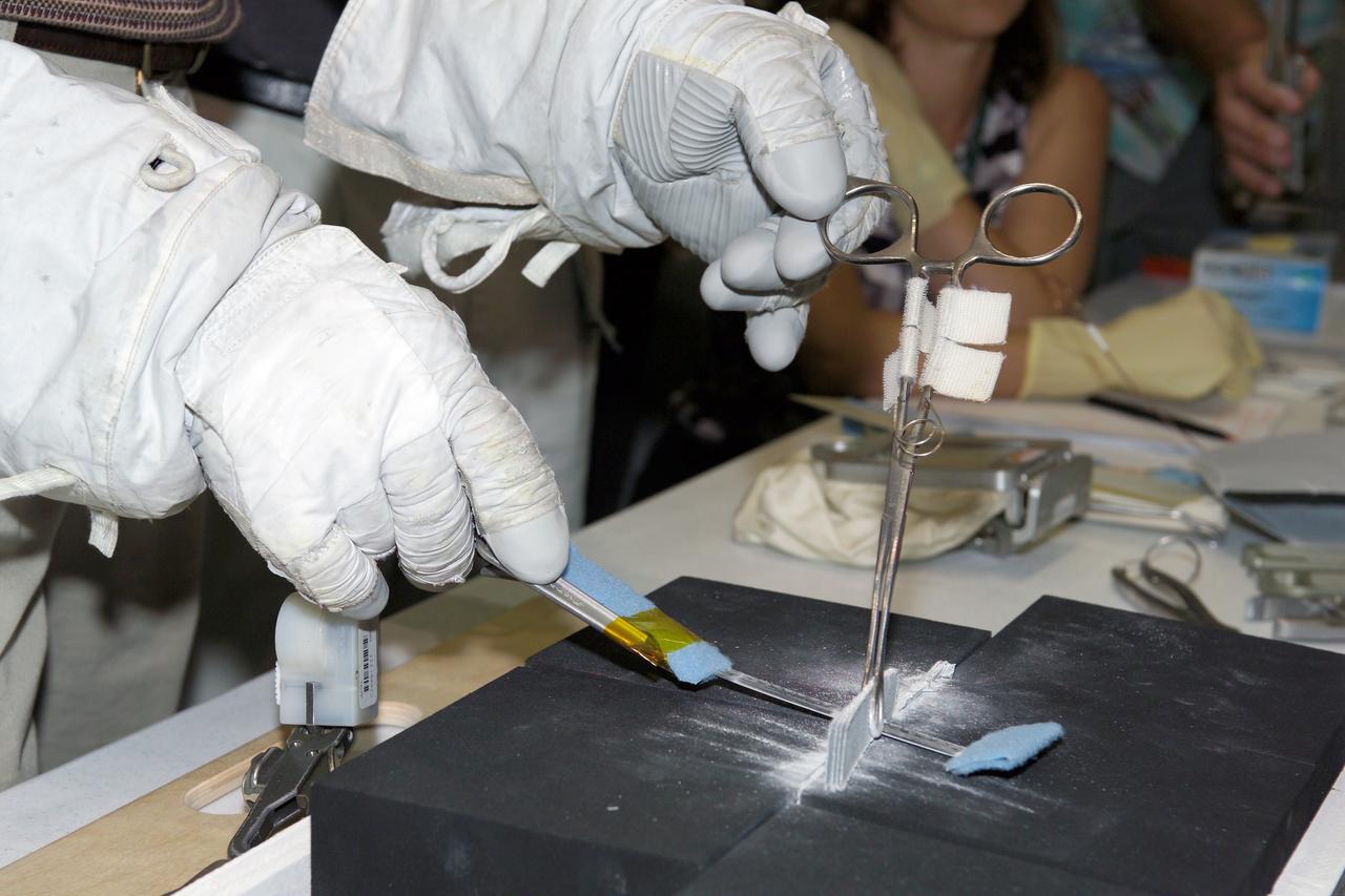 JSC2005-E-30917 (31 July 2005) --- Astronaut Joe Tanner joins other astronauts and engineers at the Johnson Space Center to practice techniques to eliminate or trim protruding gap fillers that Astronauts Noguchi and Robinson will use during their spacewalk. The ceramic coated-fabric gap fillers are used to protect against hot gas from seeping into gaps between the Shuttle’s protective tiles. Photo Credit: NASA/James Blair