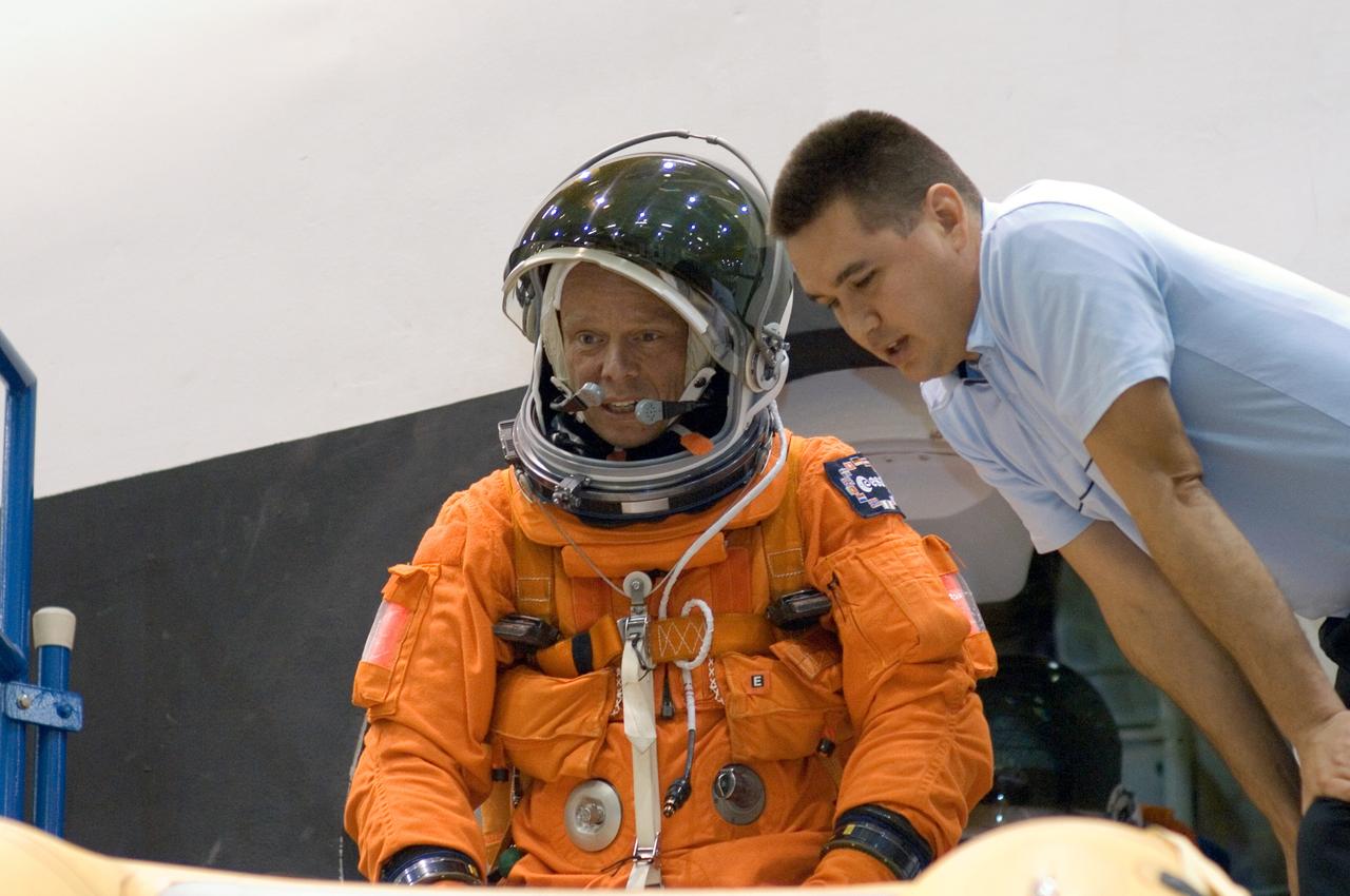 JSC2005-E-32723 (1 Aug. 2005) --- United Space Alliance (USA) crew trainer Adam Flagan briefs European Space Agency (ESA) astronaut Christer Fuglesang, STS-116 mission specialist,  on the use of the crew escape slide in the crew compartment trainer (CCT) during emergency egress training. The CCT is one of several shuttle-training components located in the Space Vehicle Mockup Facility at the Johnson Space Center. Fuglesang is wearing a training version of the shuttle launch and entry suit.