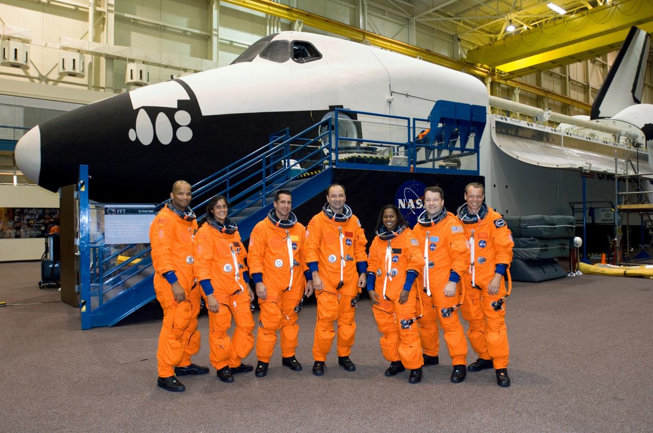 JSC2005-E-32783 (1 Aug. 2005) --- Attired in training versions of the shuttle launch and entry suit, the STS-116 crew and an Expedition 14 crewmember pose for a group photo prior to a training session in the Space Vehicle Mockup Facility at the Johnson Space Center. From the left are astronauts Robert L. Curbeam, mission specialist; Sunita L. Williams, Expedition 14 flight engineer; William A. Oefelein, pilot; Mark L. Polansky, commander; Joan E. Higginbotham, Nicholas J.M. Patrick and European Space Agency (ESA) astronaut Christer Fuglesang, all mission specialists. Williams will join Expedition 14 in progress and serve as a flight engineer after traveling to the station on space shuttle mission STS-116. The full fuselage trainer (FFT), which is a full-scale mockup of a shuttle, is visible in the background.