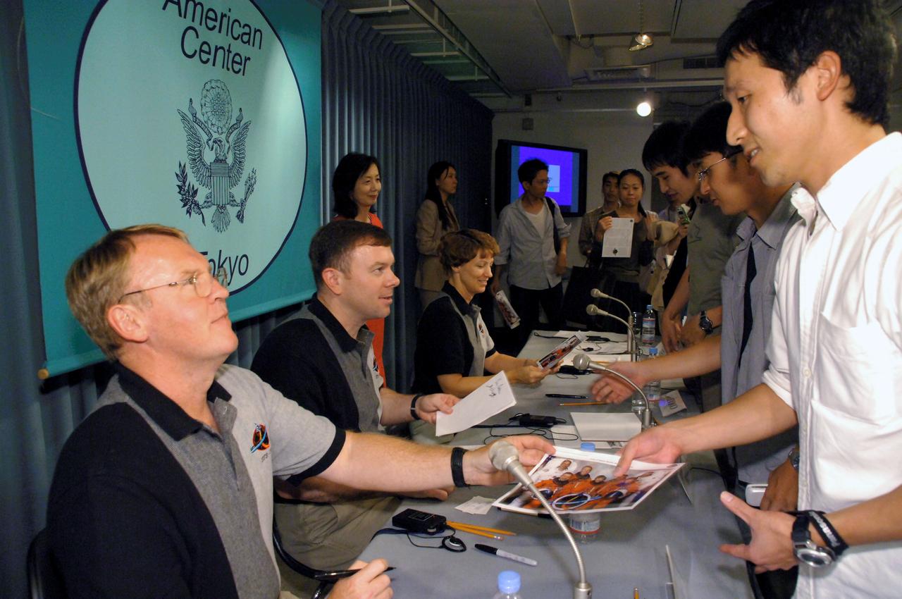 JSC2005-E-40333 (1 October 2005) --- Members of the crew that returned the Space Shuttle to flight earlier this year aboard Discovery, from left, astronauts Andrew S.W. Thomas, Pilot James M. Kelly and Discovery Commander Eileen M. Collins sign photographs for students at the American Center in Tokyo, Japan, on Oct. 1. The crew visited Japan this week as guests of the Japan Aerospace Exploration Agency (JAXA) and participated in a variety of public events.  Photo Credit: Japan Aerospace Exploration Agency