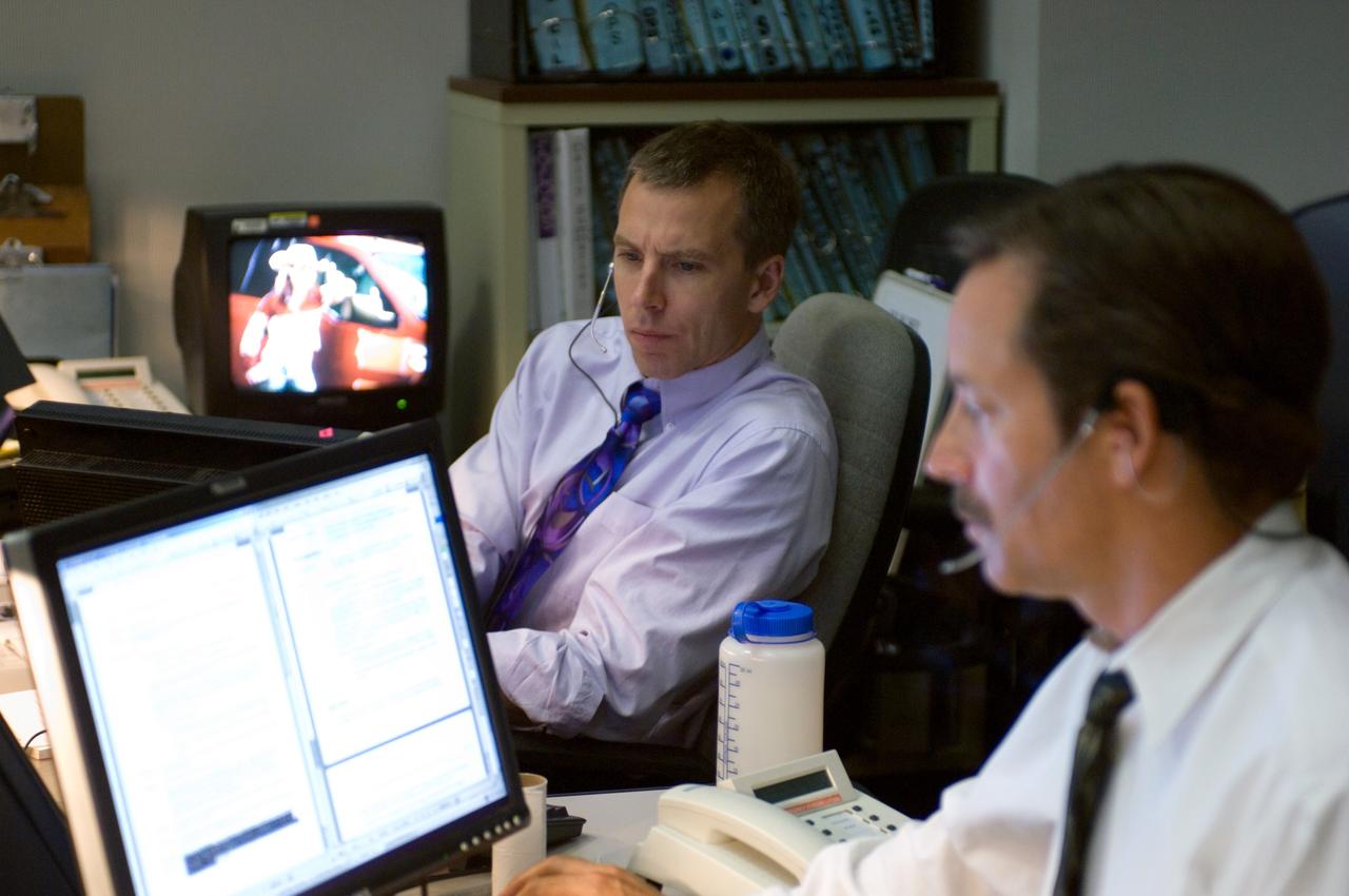 JSC2006-E-38929 (31 Aug. 2006) --- Astronaut Andrew J. Feustel (background), spacecraft communicator (CAPCOM), and flight director Rick LaBrode monitor data at their consoles in the Station (Blue) Flight Control Room in Houston's Mission Control Center during Expedition 13 mission activities.