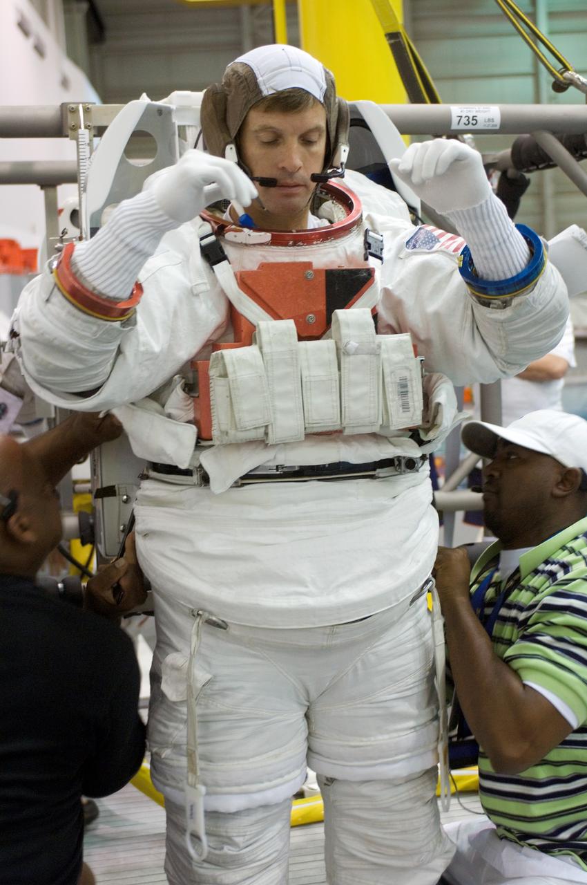 JSC2006-E-48962 (9 Nov. 2006) --- Astronaut Steven R. Swanson, STS-117 mission specialist, dons a training version of the Extravehicular Mobility Unit (EMU) spacesuit prior to being submerged in the waters of the Neutral Buoyancy Laboratory (NBL) near Johnson Space Center. Suit technicians assisted Swanson.