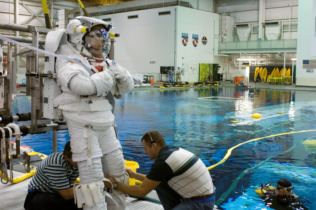 JSC2006-E-48970 (9 Nov. 2006) --- Astronaut Steven R. Swanson, STS-117 mission specialist, attired in a training version of the Extravehicular Mobility Unit (EMU) spacesuit, is about to begin a training session in the waters of the Neutral Buoyancy Laboratory (NBL) near the Johnson Space Center. Suit technicians assisted Swanson with the final touches in the donning process.