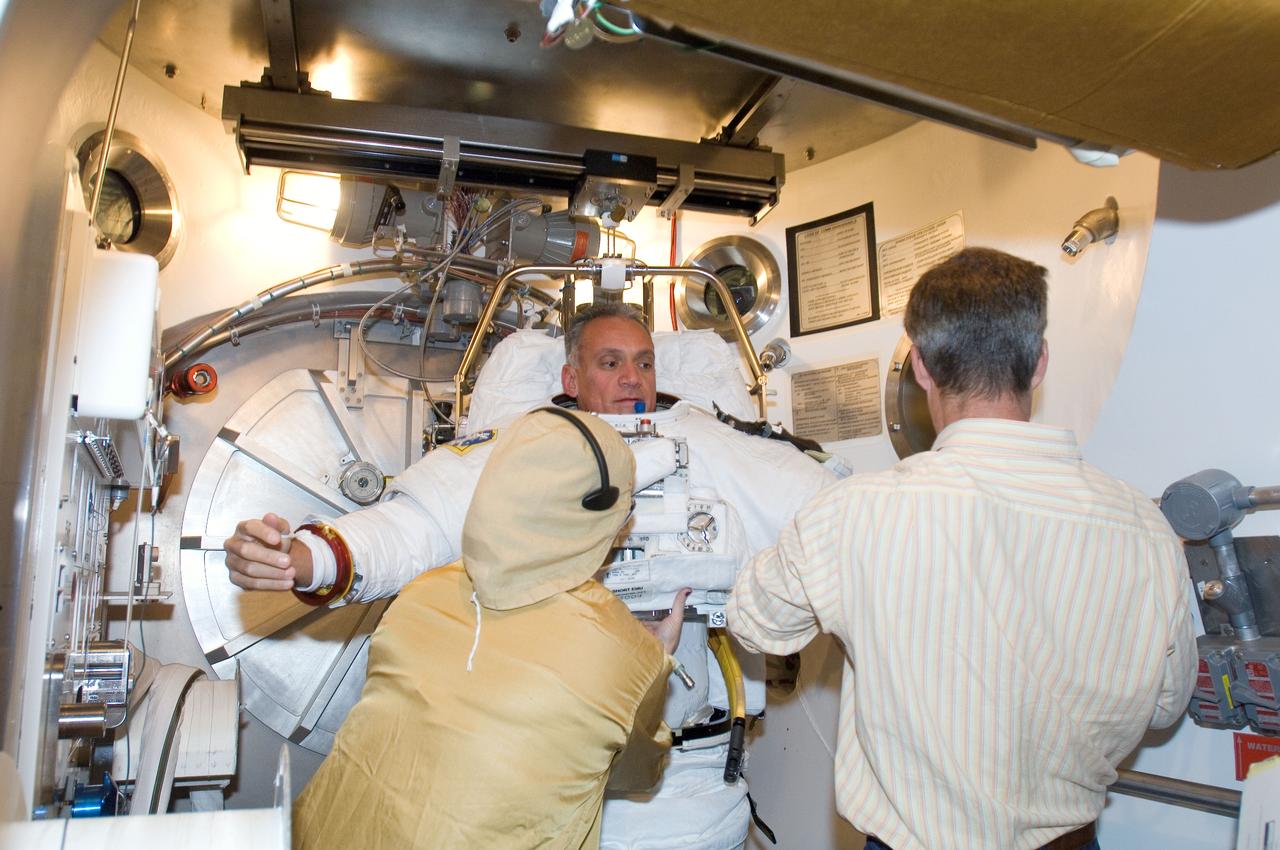 JSC2006-E-53013 (4 Dec. 2006) --- Astronaut John D. (Danny) Olivas, STS-117 mission specialist, participates in an Extravehicular Mobility Unit (EMU) spacesuit fit check in the Space Station Airlock Test Article (SSATA) in the Crew Systems Laboratory at the Johnson Space Center. Astronaut Steven R. Swanson (right), mission specialist, and a suit technician assisted Olivas.