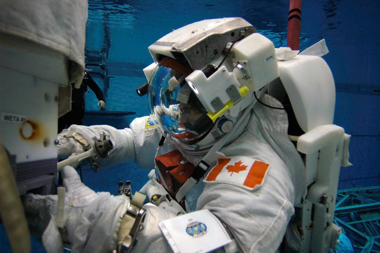 JSC2007-E-26262 (4 April 2007) --- Astronaut Dafydd R. (Dave) Williams, STS-118 mission specialist representing the Canadian Space Agency, wearing a training version of the Extravehicular Mobility Unit (EMU) spacesuit, participates in an underwater simulation of extravehicular activity (EVA) in the Neutral Buoyancy Laboratory (NBL) near Johnson Space Center. SCUBA-equipped divers are in the water to assist Williams in his rehearsal, intended to help prepare him for work on the exterior of the International Space Station.