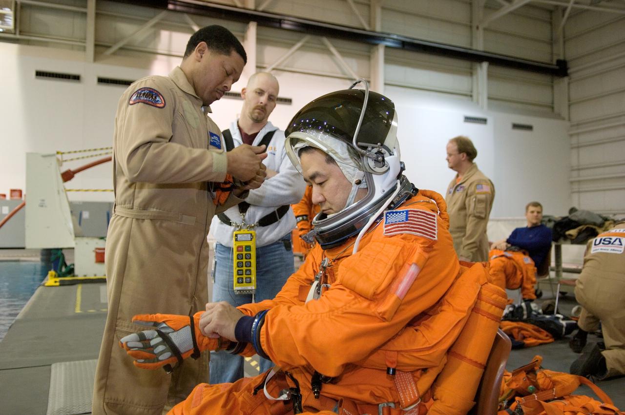 JSC2007-E-06411 (31 Jan. 2007) --- Astronaut Daniel M. Tani, Expedition 16 flight engineer, dons a training version of his shuttle launch and entry suit in preparation for a water survival training session in the Neutral Buoyancy Laboratory (NBL) near Johnson Space Center. United Space Alliance (USA) suit technician George Brittingham assisted Tani, who will join Expedition 16 as flight engineer after launching to the International Space Station aboard Atlantis on mission STS-120 and will return home aboard Discovery on mission STS-122.