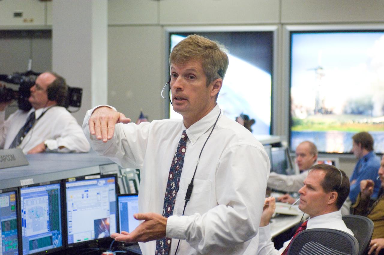 JSC2007-E-095996 (3 Nov. 2007) ---Astronaut Steve Swanson, standing near the spacecraft communicator (CAPCOM) console in the space station control room of JSC's Mission Control Center, communicates with astronauts in space during the Nov. 3 spacewalk planned to repair a tear in a solar panel on the International Space Station.