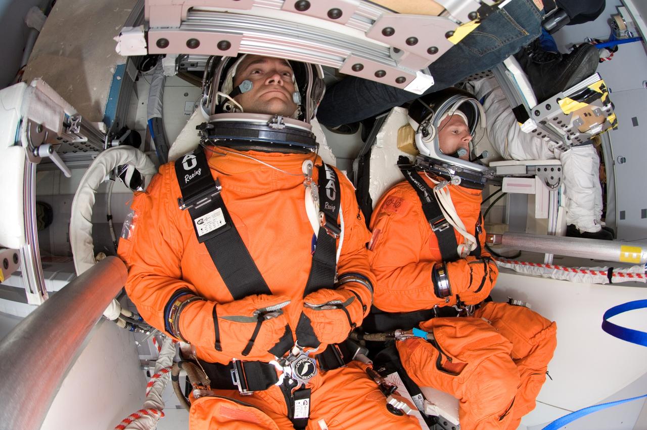 Photographic documentation of the CEV Seat Layout Evaluation taken in the Orion mockup located in bldg 9NW, Johnson Space Center (JSC).  Test subjects in orange Launch and Entry Suit (LES) is visible in the seat.