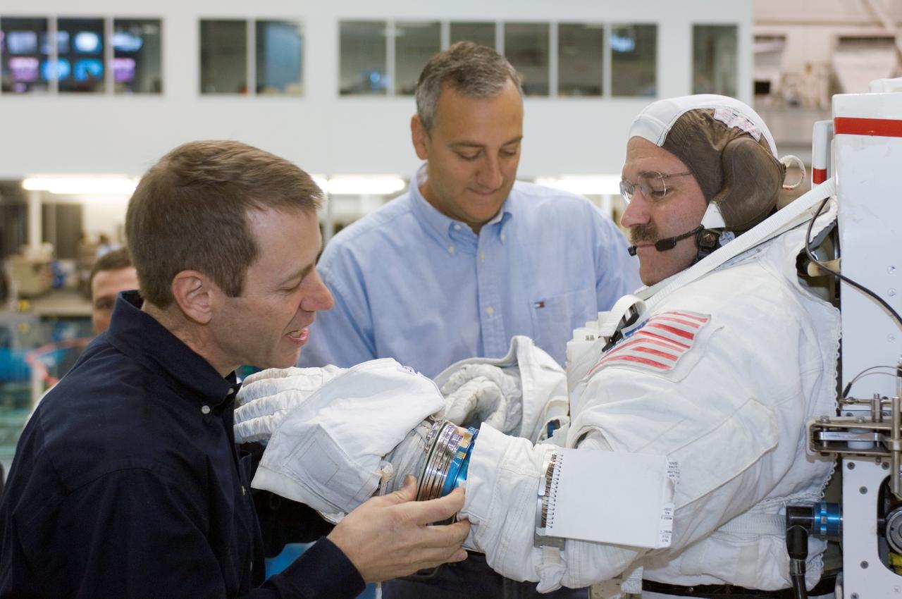 JSC2007-E-113485 (17 Dec. 2007) --- Astronaut John M. Grunsfeld, STS-125 mission specialist, dons a training version of the Extravehicular Mobility Unit (EMU) spacesuit prior to being submerged in the waters of the Neutral Buoyancy Laboratory (NBL) near the Johnson Space Center. Astronauts Andrew J. Feustel (left) and Michael J. Massimino, both mission specialists, assisted Grunsfeld.