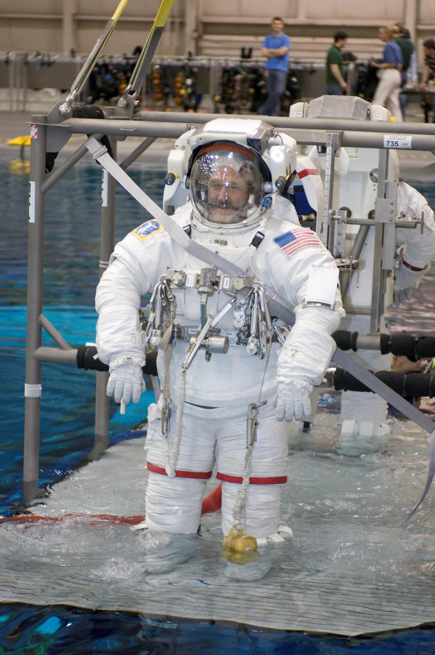 JSC2007-E-113498 (17 Dec. 2007) --- Astronauts John M. Grunsfeld and Andrew J. Feustel (partially obscured), both STS-125 mission specialists, are about to be submerged in the waters of the Neutral Buoyancy Laboratory (NBL) near Johnson Space Center. Grunsfeld and Feustel are attired in training versions of the Extravehicular Mobility Unit (EMU) spacesuit. SCUBA-equipped divers (out of frame) are in the water to assist the crewmembers in their rehearsal, intended to help prepare them for work on the Hubble Space Telescope.