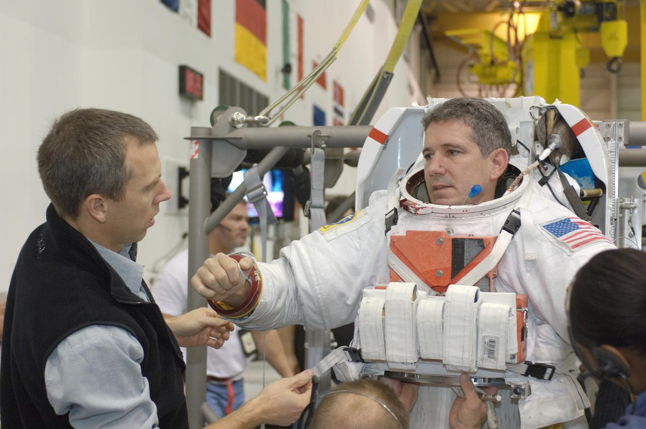 JSC2007-E-113592 (18 Dec. 2007) --- Astronaut Michael T. Good, STS-125 mission specialist, dons a training version of the Extravehicular Mobility Unit (EMU) spacesuit prior to being submerged in the waters of the Neutral Buoyancy Laboratory (NBL) near the Johnson Space Center. Astronaut Andrew J. Feustel (left), mission specialist, assisted Good.