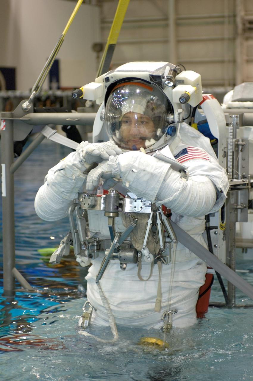 JSC2007-E-113611 (18 Dec. 2007) --- Astronauts Michael J. Massimino and Michael T. Good (partially obscured), both STS-125 mission specialists, are about to be submerged in the waters of the Neutral Buoyancy Laboratory (NBL) near Johnson Space Center. Massimino and Good are attired in training versions of the Extravehicular Mobility Unit (EMU) spacesuit. SCUBA-equipped divers (out of frame) are in the water to assist the crewmembers in their rehearsal, intended to help prepare them for work on the Hubble Space Telescope.