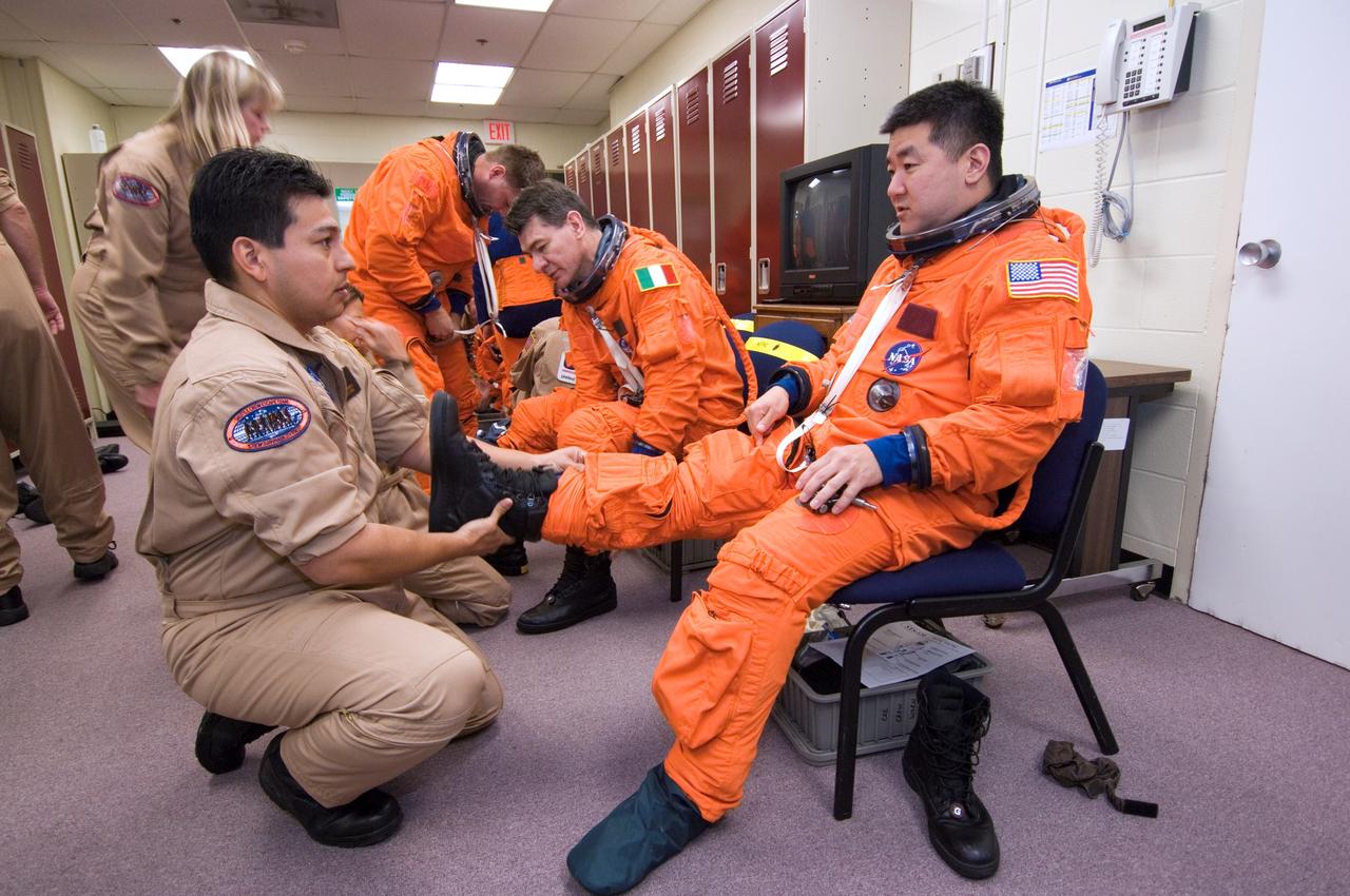 JSC2007-E-18060 (9 April 2007) --- Astronauts Daniel M. Tani (foreground right), Expedition 16 flight engineer; European Space Agency's (ESA) Paolo Nespoli (background right) and Douglas H. Wheelock (background center), both STS-120 mission specialists, don training versions of their shuttle launch and entry suits in preparation for a training session in the Space Vehicle Mockup Facility at the Johnson Space Center. Tani is scheduled to join Expedition 16 as flight engineer after launching to the International Space Station on mission STS-120 and is scheduled to return home on mission STS-122. United Space Alliance suit technician Ryan Carabaja assisted Tani.