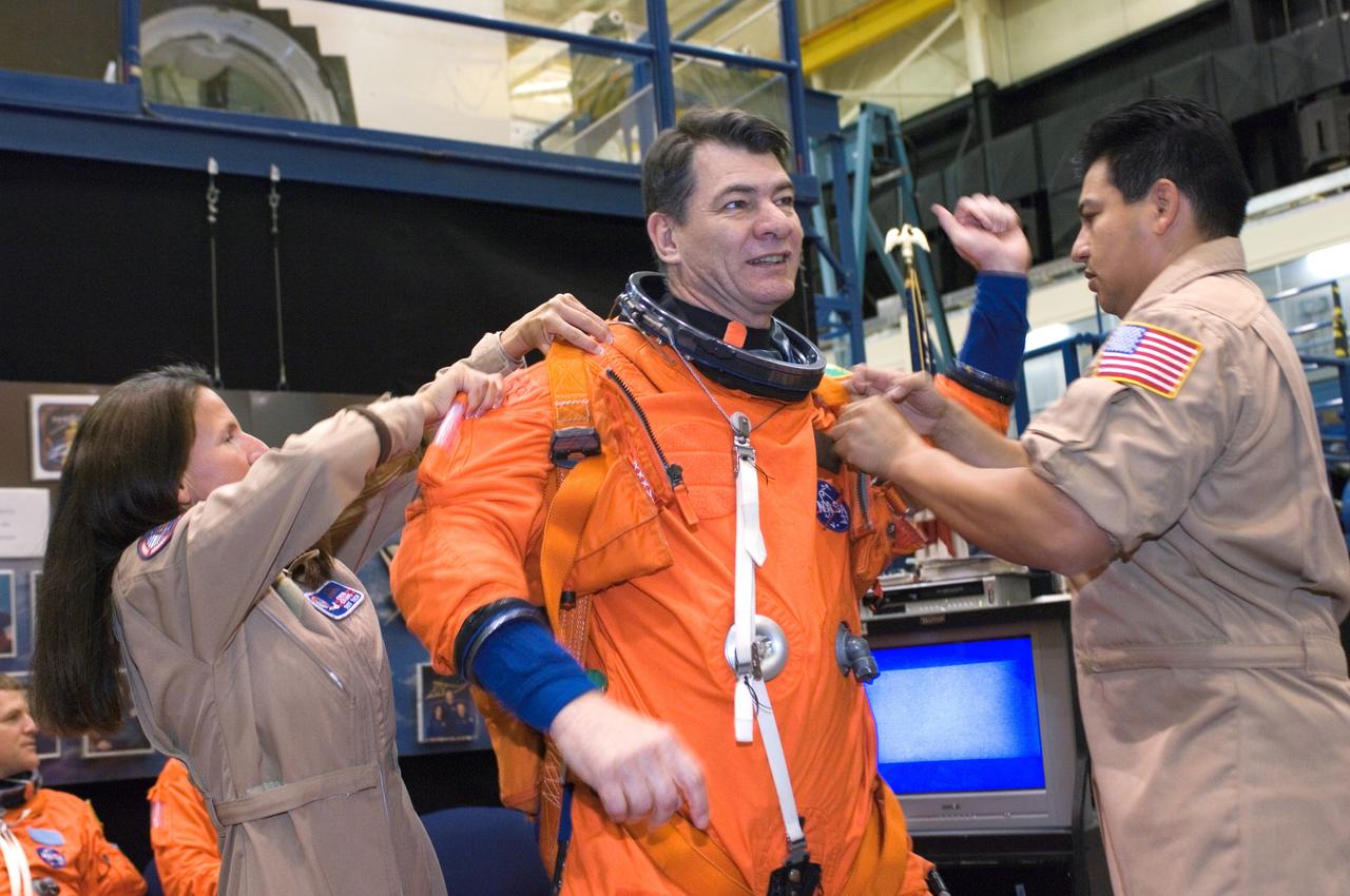 JSC2007-E-18065 (9 April 2007) --- European Space Agency (ESA) astronaut Paolo Nespoli, STS-120 mission specialist, dons a training version of his shuttle launch and entry suit in preparation for a training session in the Space Vehicle Mockup Facility at the Johnson Space Center. United Space Alliance suit technicians Toni Cost-Davis (left) and Ryan Carabaja assisted Nespoli.