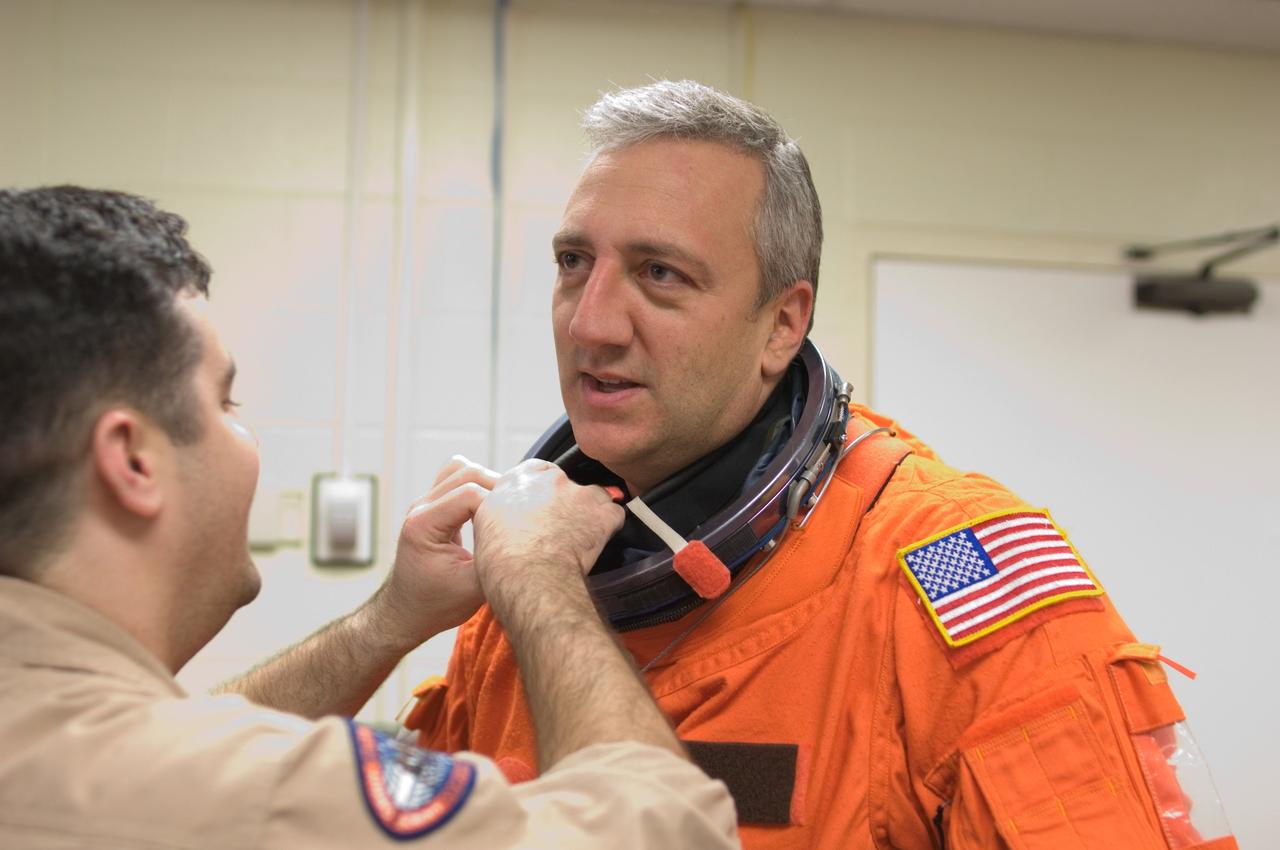 JSC2008-E-008424 (29 Jan. 2008) --- Astronaut Michael J. Massimino, STS-125 mission specialist, dons a training version of his shuttle launch and entry suit in preparation for a training session in the Space Vehicle Mockup Facility at Johnson Space Center. United Space Alliance (USA) suit technician Carlos E. Ramos assisted Massimino.
