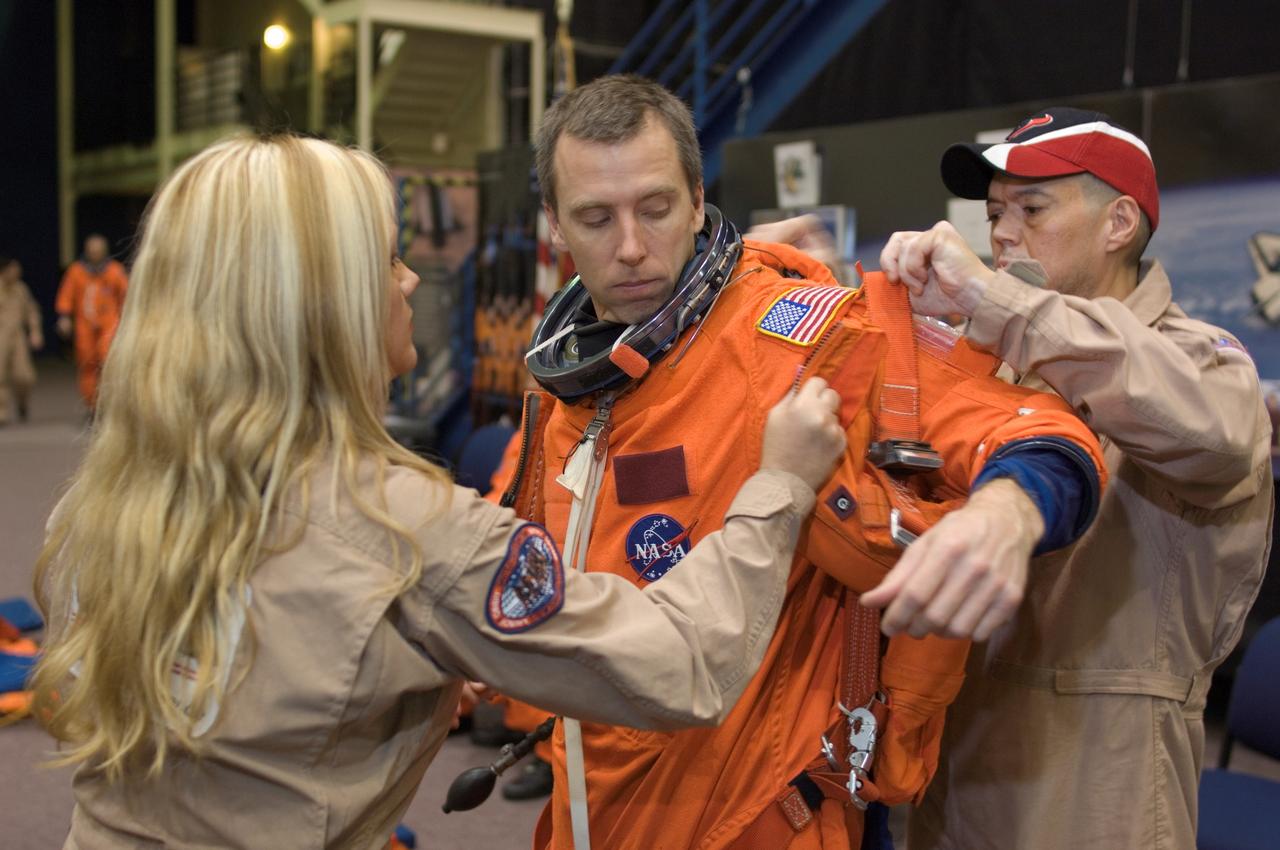 JSC2008-E-008443 (29 Jan. 2008) --- Astronaut Andrew J. Feustel, STS-125 mission specialist, dons a training version of his shuttle launch and entry suit in preparation for a training session in the Space Vehicle Mockup Facility at Johnson Space Center. United Space Alliance (USA) suit technicians Nicole Everett and Steve Cortinas assisted Feustel.