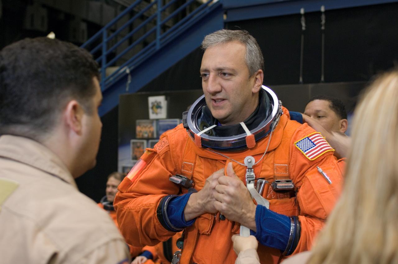 JSC2008-E-008449 (29 Jan. 2008) --- Astronaut Michael J. Massimino, STS-125 mission specialist, dons a training version of his shuttle launch and entry suit in preparation for a training session in the Space Vehicle Mockup Facility at Johnson Space Center. United Space Alliance (USA) suit technicians assisted Massimino.