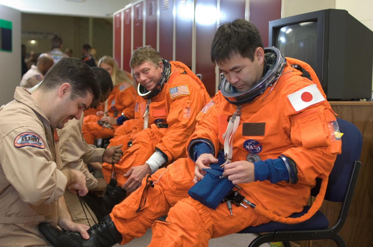 JSC2008-E-009419 (31 Jan. 2008) --- Japan Aerospace Exploration Agency (JAXA) astronaut Akihiko Hoshide (right), STS-124 mission specialist, dons a training version of his shuttle launch and entry suit in preparation for a training session in the Space Vehicle Mockup Facility at Johnson Space Center. United Space Alliance suit technician Carlos Ramos assisted Hoshide. Astronaut Michael E. Fossum, mission specialist, is also visible.