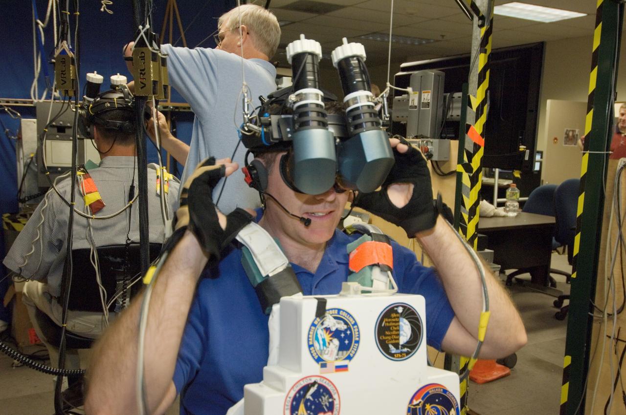 JSC2008-E-033766 (14 April 2008) --- Astronauts Stephen G. Bowen (foreground) and Robert S. (Shane) Kimbrough, both STS-126 mission specialists, use virtual reality hardware in the Space Vehicle Mockup Facility at NASA's Johnson Space Center to rehearse some of their duties on the upcoming mission to the International Space Station. This type of virtual reality training allows the astronauts to wear special gloves and other gear while looking at computer displays simulating actual movements around the various locations on the station hardware with which they will be working. David J. Homan assisted Bowen and Kimbrough.