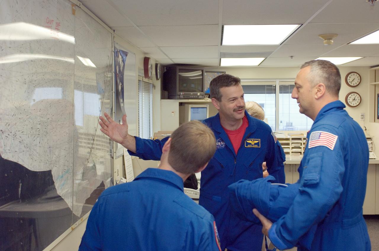 JSC2008-E-035352 (17 April 2008) --- Astronauts Scott D. Altman (center), Gregory C. Johnson (foreground), STS-125 commander and pilot, respectively, and Michael J. Massimino, mission specialist, look over their flight plan in the check-out facility at Ellington Field near NASA's Johnson Space Center prior to a flight in NASA T-38 trainer jets.
