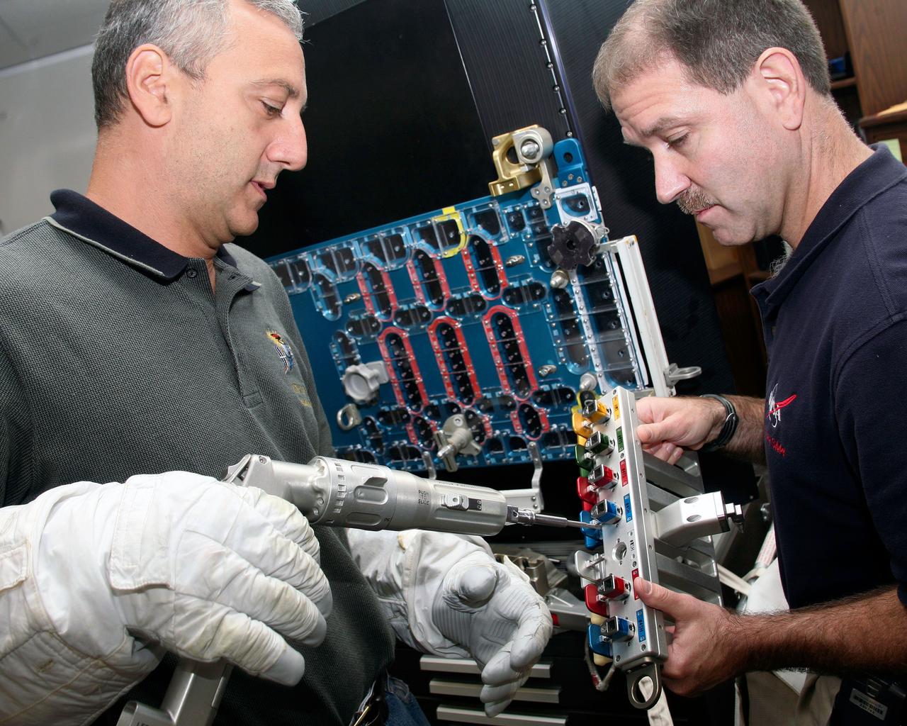 JSC2008-E-097093 (1 Aug. 2008) --- Astronauts Mike Massimino (left) and John Grunsfeld, both STS-125 mission specialists, practice repairing Hubble Space Telescope hardware during a training session at NASA's Johnson Space Center.