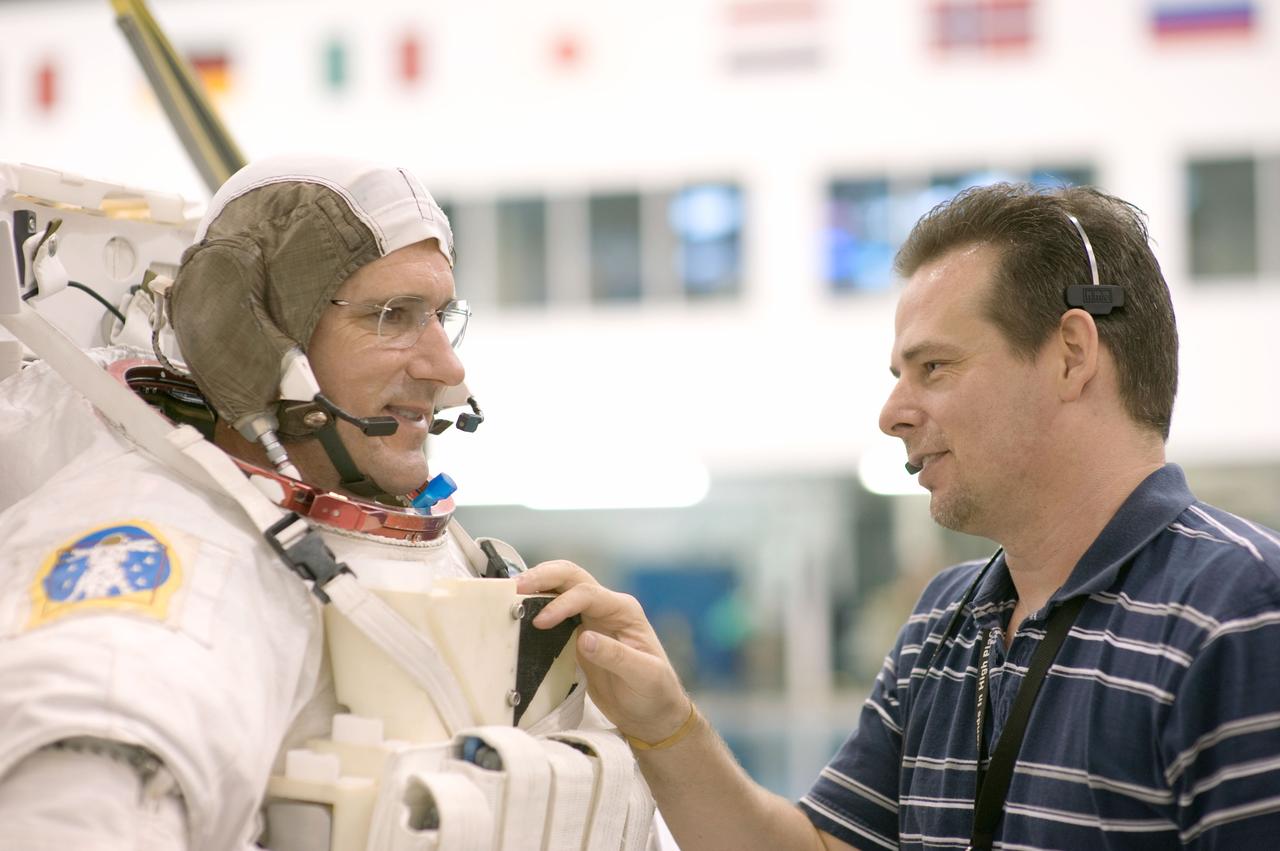 JSC2008-E-118364 (25 Sept. 2008) --- Astronaut Michael Good (left), STS-125 mission specialist, and United Space Alliance suit technician Beau Webb discuss training activities in the Neutral Buoyancy Laboratory (NBL) near NASA's Johnson Space Center. Good is wearing a training version of his Extravehicular Mobility Unit (EMU) spacesuit.