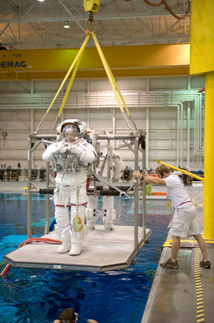 JSC2008-E-118378 (25 Sept. 2008) --- Astronauts Mike Massimino and Michael Good (partially obscured), both STS-125 mission specialists, are about to be submerged in the waters of the Neutral Buoyancy Laboratory (NBL) near NASA's Johnson Space Center. Massimino and Good are attired in training versions of their Extravehicular Mobility Unit (EMU) spacesuit. SCUBA-equipped divers (out of frame) are in the water to assist the crewmembers in their rehearsal, intended to help prepare them for work on the Hubble Space Telescope.