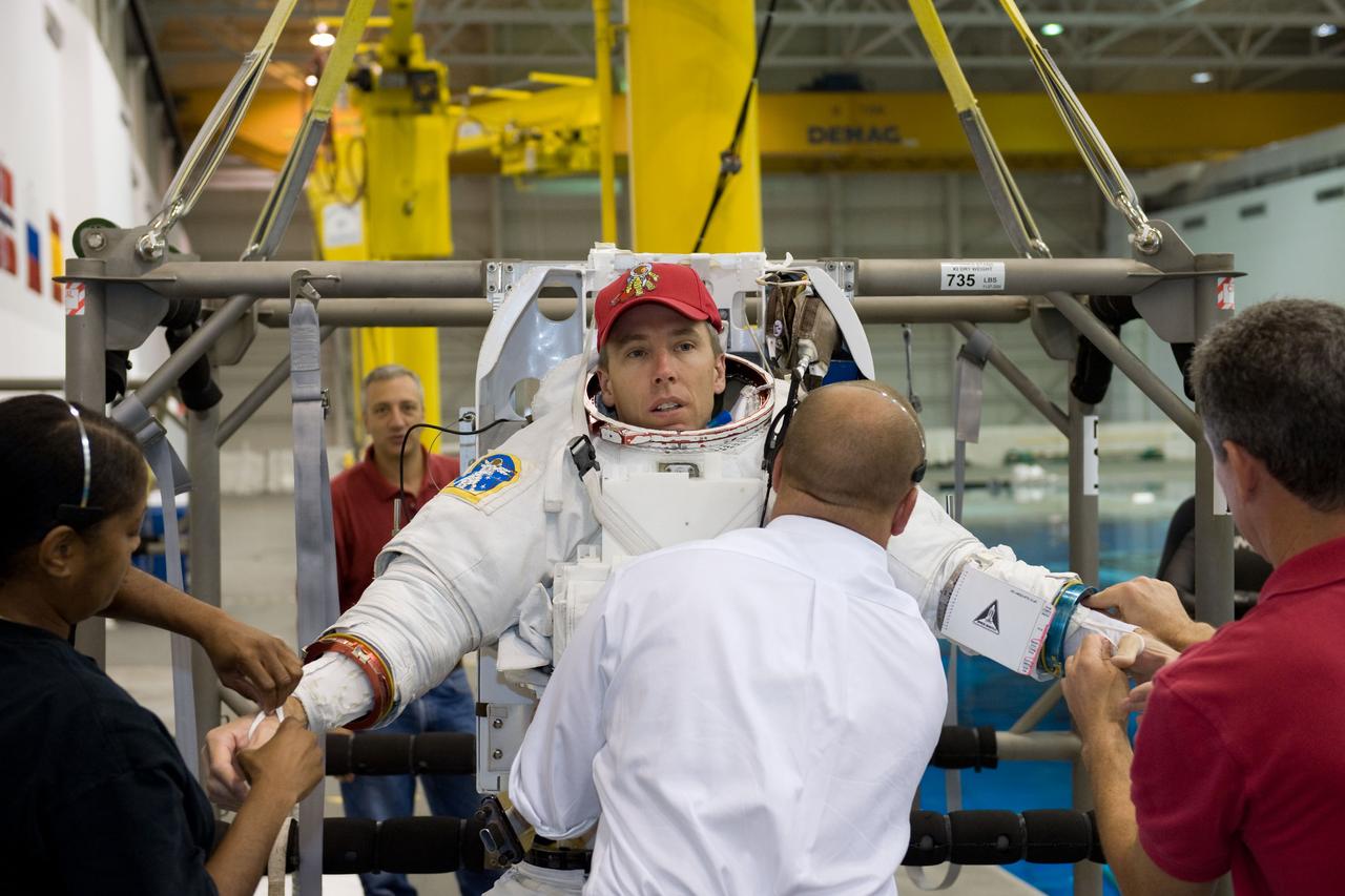 JSC2008-E-118404 (26 Sept. 2008) --- Astronaut Andrew Feustel, STS-125 mission specialist, gets help in the donning of a training version of the Extravehicular Mobility Unit (EMU) spacesuit prior to being submerged in the waters of the Neutral Buoyancy Laboratory (NBL) near NASA's Johnson Space Center.