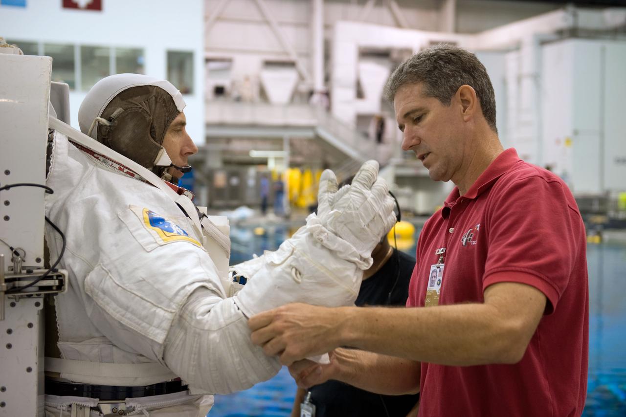 JSC2008-E-118410 (26 Sept. 2008) --- Astronaut Andrew Feustel, STS-125 mission specialist, dons a training version of his Extravehicular Mobility Unit (EMU) spacesuit in preparation for a training session in the waters of the Neutral Buoyancy Laboratory (NBL) near NASA's Johnson Space Center. Astronaut Michael Good, mission specialist, assisted Feustel.