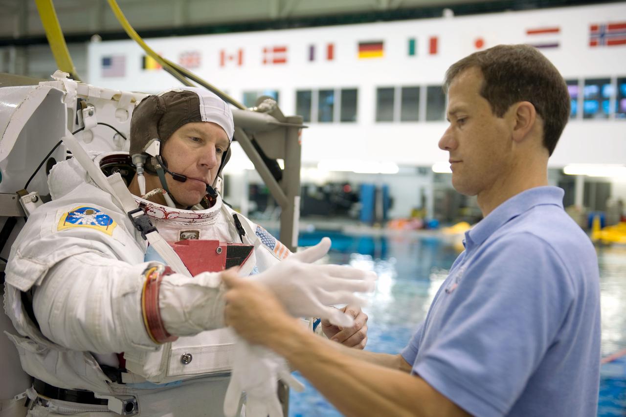 JSC2008-E-122385 (9 Oct. 2008) --- Astronaut Tim Kopra, STS-127 mission specialist, dons a training version of his Extravehicular Mobility Unit (EMU) spacesuit in preparation for a training session in the waters of the Neutral Buoyancy Laboratory (NBL) near NASA's Johnson Space Center. Astronaut Tom Marshburn, mission specialist, assisted Kopra, who is scheduled to join Expedition 19 as flight engineer after launching to the International Space Station with the STS-127 crew.