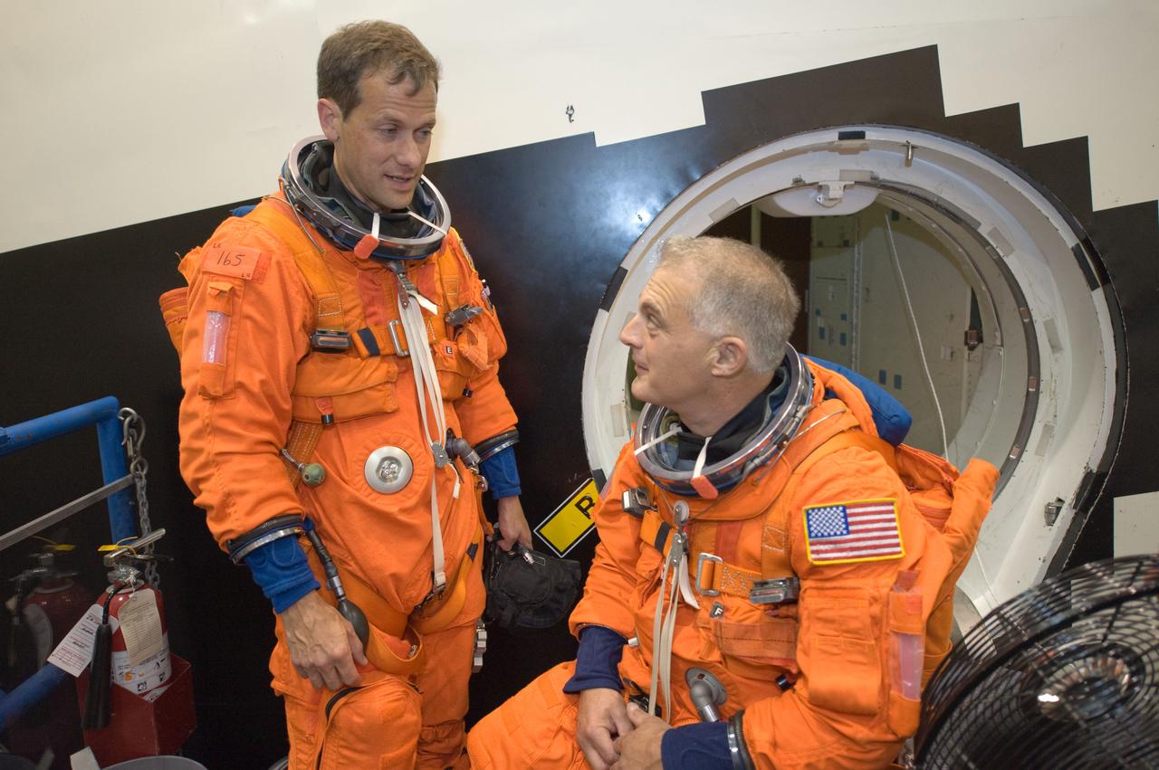 JSC2008-E-122430 (7 Oct. 2008) --- Attired in training versions of their shuttle launch and entry suits, astronauts Tom Marshburn (left) and Dave Wolf, both STS-127 mission specialists, exchange ideas during a training session in the Space Vehicle Mock-up Facility at NASA's Johnson Space Center.