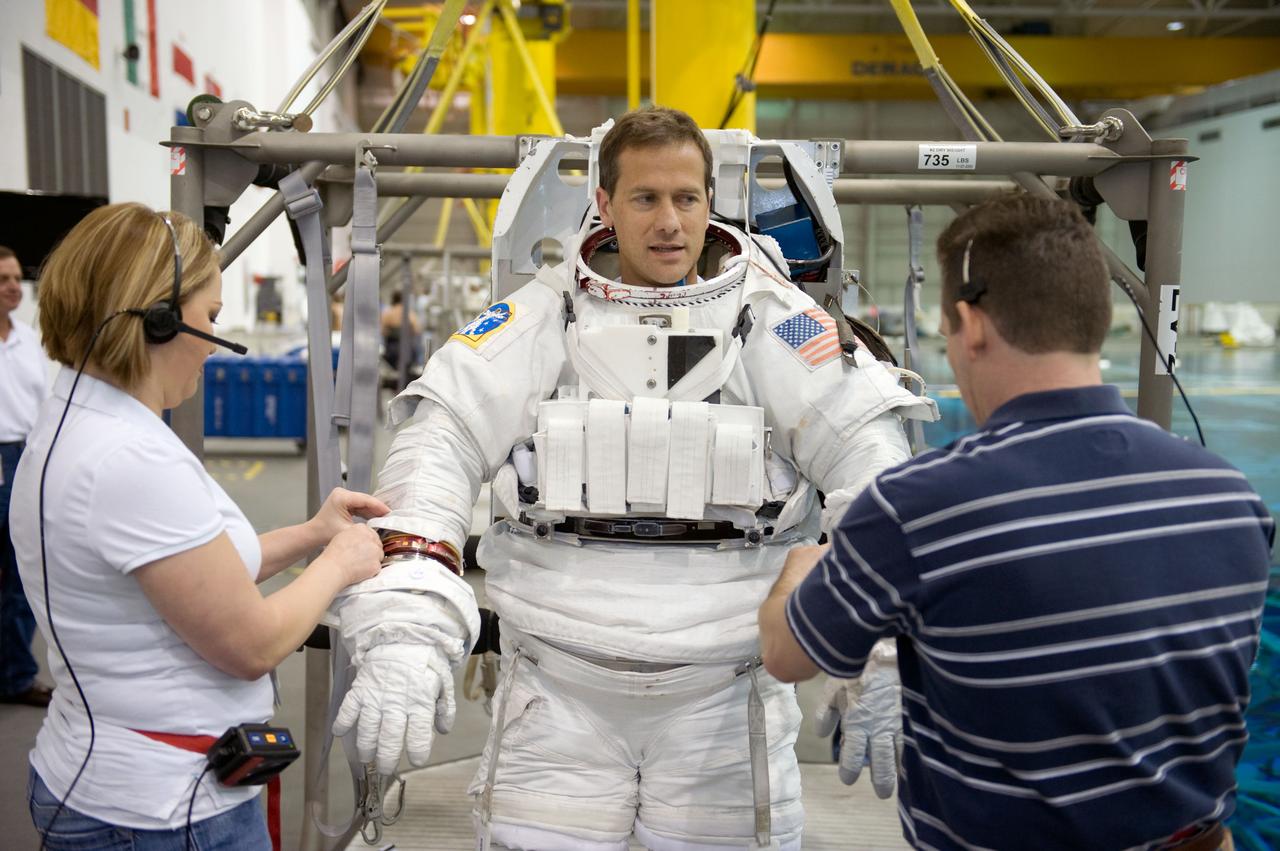JSC2008-E-124035 (20 Oct. 2008) --- Astronaut Tom Marshburn, STS-127 mission specialist, gets help with the donning of a training version of his Extravehicular Mobility Unit (EMU) spacesuit in preparation for a training session in the waters of the Neutral Buoyancy Laboratory (NBL) near NASA's Johnson Space Center.
