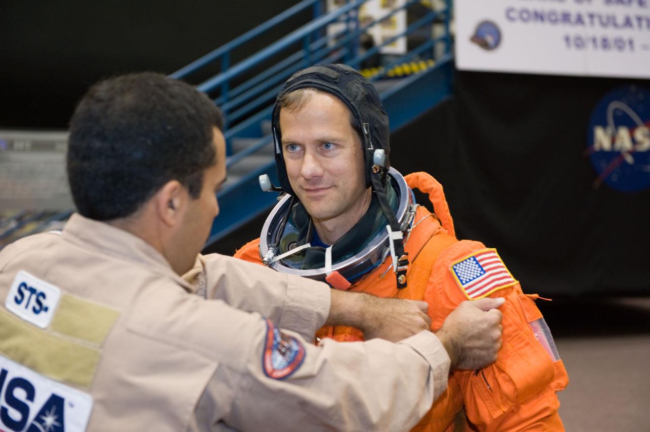 JSC2008-E-139788 (12 Nov. 2008) --- Astronaut Tom Marshburn, STS-127 mission specialist, dons a training version of his shuttle launch and entry suit in preparation for a training session in the Space Vehicle Mock-up Facility at NASA's Johnson Space Center. United Space Alliance (USA) suit technician Raymond Cuevas assisted Marshburn.