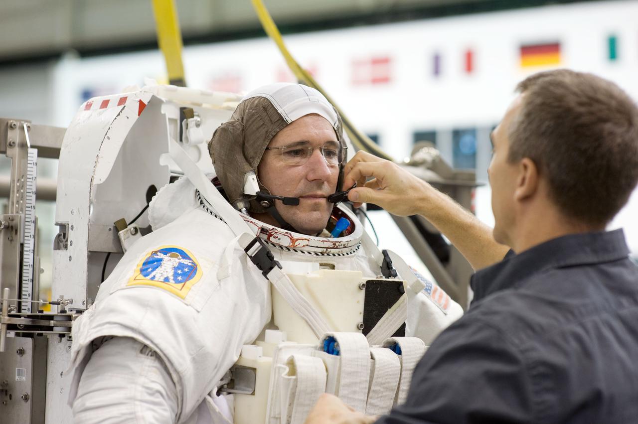 JSC2008-E-141517 (6 Nov. 2008) --- Astronaut Michael Good, STS-125 mission specialist, dons a training version of his Extravehicular Mobility Unit (EMU) spacesuit prior to being submerged in the waters of the Neutral Buoyancy Laboratory (NBL) near NASA's Johnson Space Center. Astronaut Andrew Feustel, mission specialist, assisted Good.