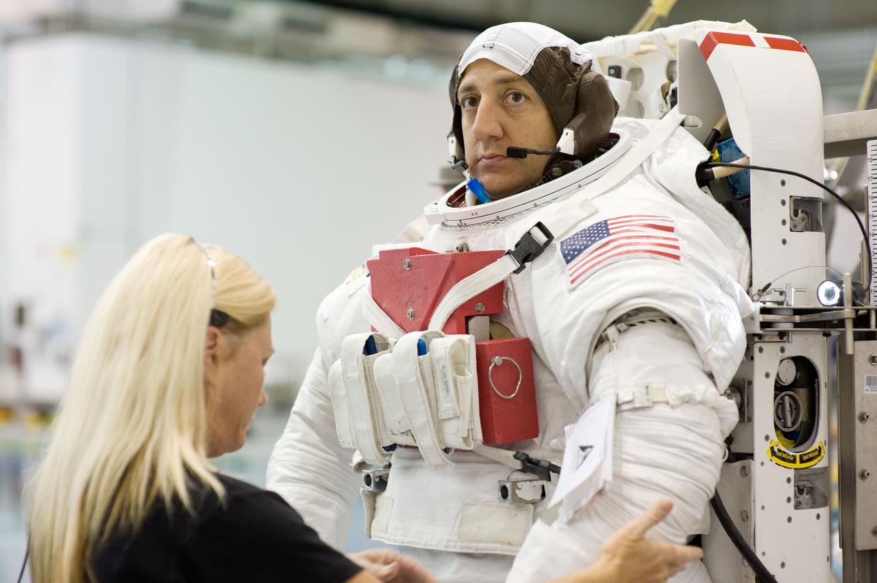JSC2008-E-141520 (6 Nov. 2008) --- Astronaut Mike Massimino, STS-125 mission specialist, gets help in the donning a training version of his Extravehicular Mobility Unit (EMU) spacesuit prior to being submerged in the waters of the Neutral Buoyancy Laboratory (NBL) near NASA's Johnson Space Center.
