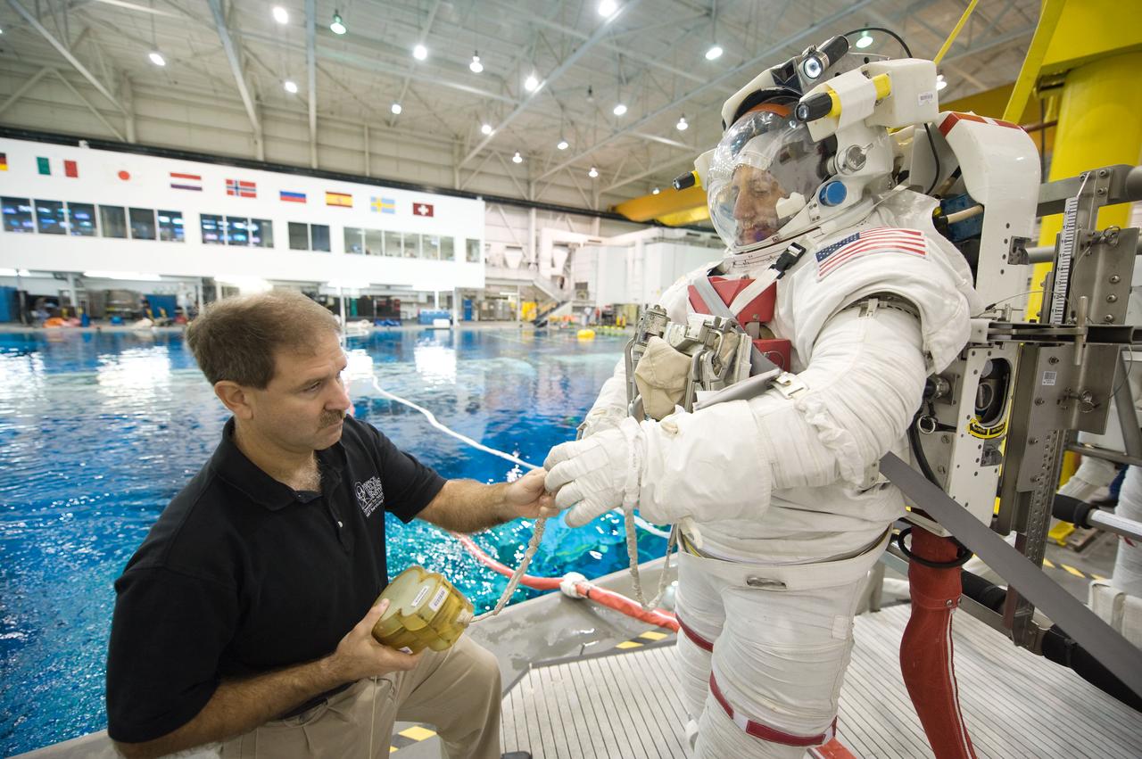 JSC2008-E-141528 (6 Nov. 2008) --- Astronaut Mike Massimino, STS-125 mission specialist, gets help with final touches in the donning of a training version of his Extravehicular Mobility Unit (EMU) spacesuit prior to being submerged in the waters of the Neutral Buoyancy Laboratory (NBL) near NASA's Johnson Space Center. Astronaut John Grunsfeld, mission specialist, assisted Massimino.