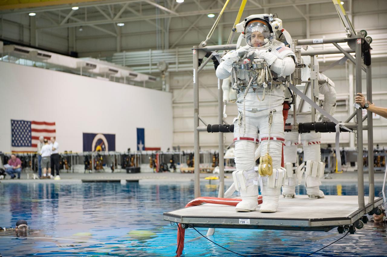 JSC2008-E-141532 (6 Nov. 2008) --- Astronauts Mike Massimino and Michael Good (partially obscured), both STS-125 mission specialists, are about to be submerged in the waters of the Neutral Buoyancy Laboratory (NBL) near NASA's Johnson Space Center. Massimino and Good are attired in training versions of their Extravehicular Mobility Unit (EMU) spacesuit. SCUBA-equipped divers are in the water to assist the crewmembers in their rehearsal, intended to help prepare them for work on the Hubble Space Telescope.