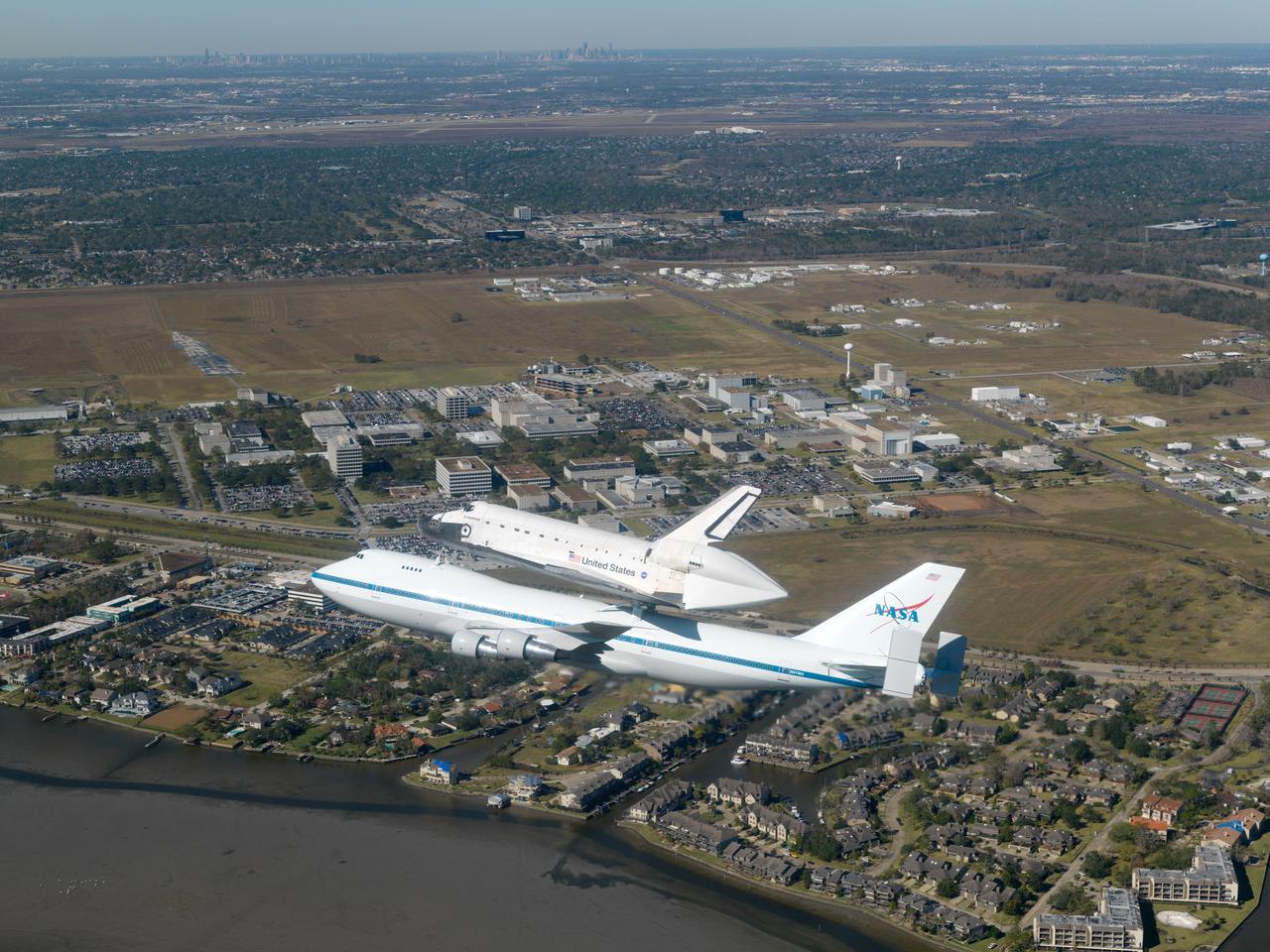 JSC2008-E-154359 (11 Dec. 2008) --- The Space Shuttle Endeavour flies over the Clear Lake area and the Johnson Space Center after having spent the night at a stopover in Tarrant County, while mounted on a modified Boeing 747 shuttle carrier aircraft. Endeavour landed in California on Nov. 30 and was en route back to Florida.  This photo, taken from the rear station of a NASA T-38 aircraft, shows the main part of the 1625-acre JSC site.  The extremely clear weather allows viewing all the way to Houston's central business district. Harris County Domed Stadium and the Houston NFL franchise's stadium are visible in the upper left quadrant of the photo.