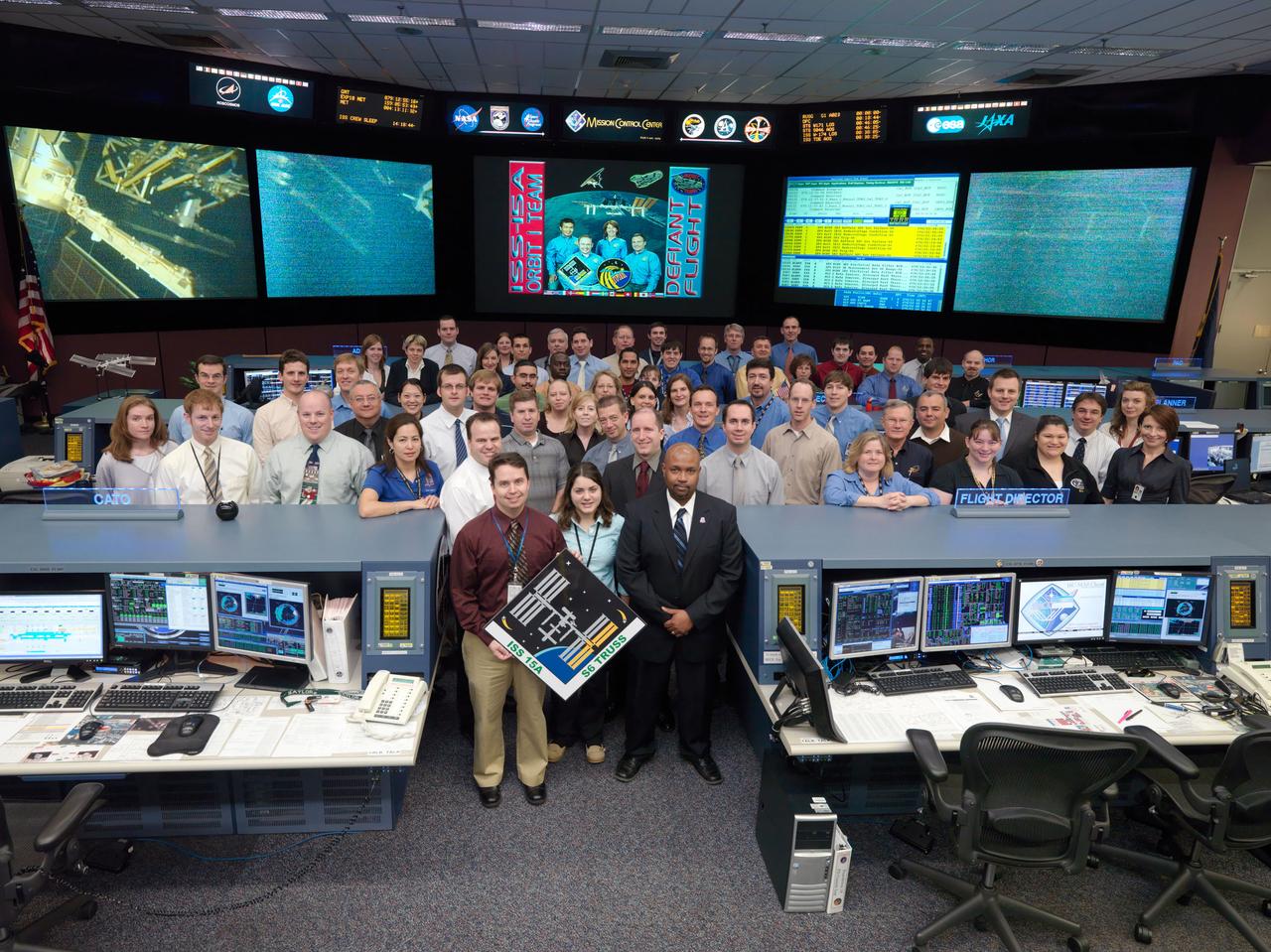 JSC2009-E-060959 (20 March 2009) --- The members of the STS-119/15A ISS Orbit 1 flight control team pose for a group portrait in the space station flight control room in the Mission Control Center at NASA’s Johnson Space Center. Flight director Kwatsi Alibaruho (right) is visible on the front row.