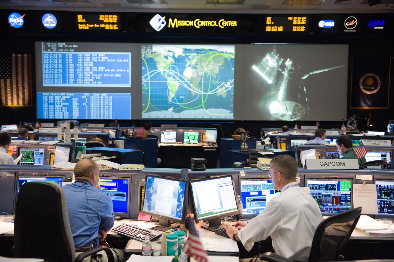 JSC2009-E-119745 (13 May 2009) --- Flight director Tony Ceccacci (left) and astronaut Dan Burbank, STS-125 spacecraft communicator (CAPCOM), monitor data at their consoles in the space shuttle flight control room in the Mission Control Center at NASA's Johnson Space Center during flight day three activities. The Hubble Space Telescope, grappled by Space Shuttle Atlantis? remote manipulator system (RMS), is visible on one of the big screens.