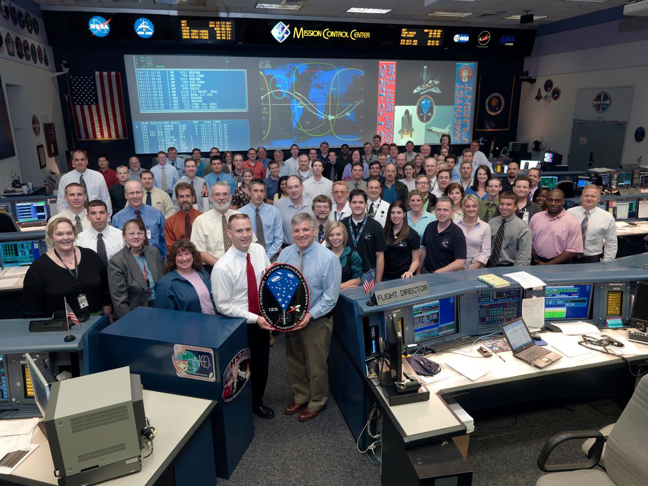 JSC2009-E-121353 (21 May 2009) --- The members of the STS-125 Ascent and Entry flight control team pose for a group portrait in the space shuttle flight control room in the Mission Control Center at NASA's Johnson Space Center. Flight director Norm Knight (left) and astronaut Gregory H. Johnson, spacecraft communicator (CAPCOM), hold the STS-125 mission logo.