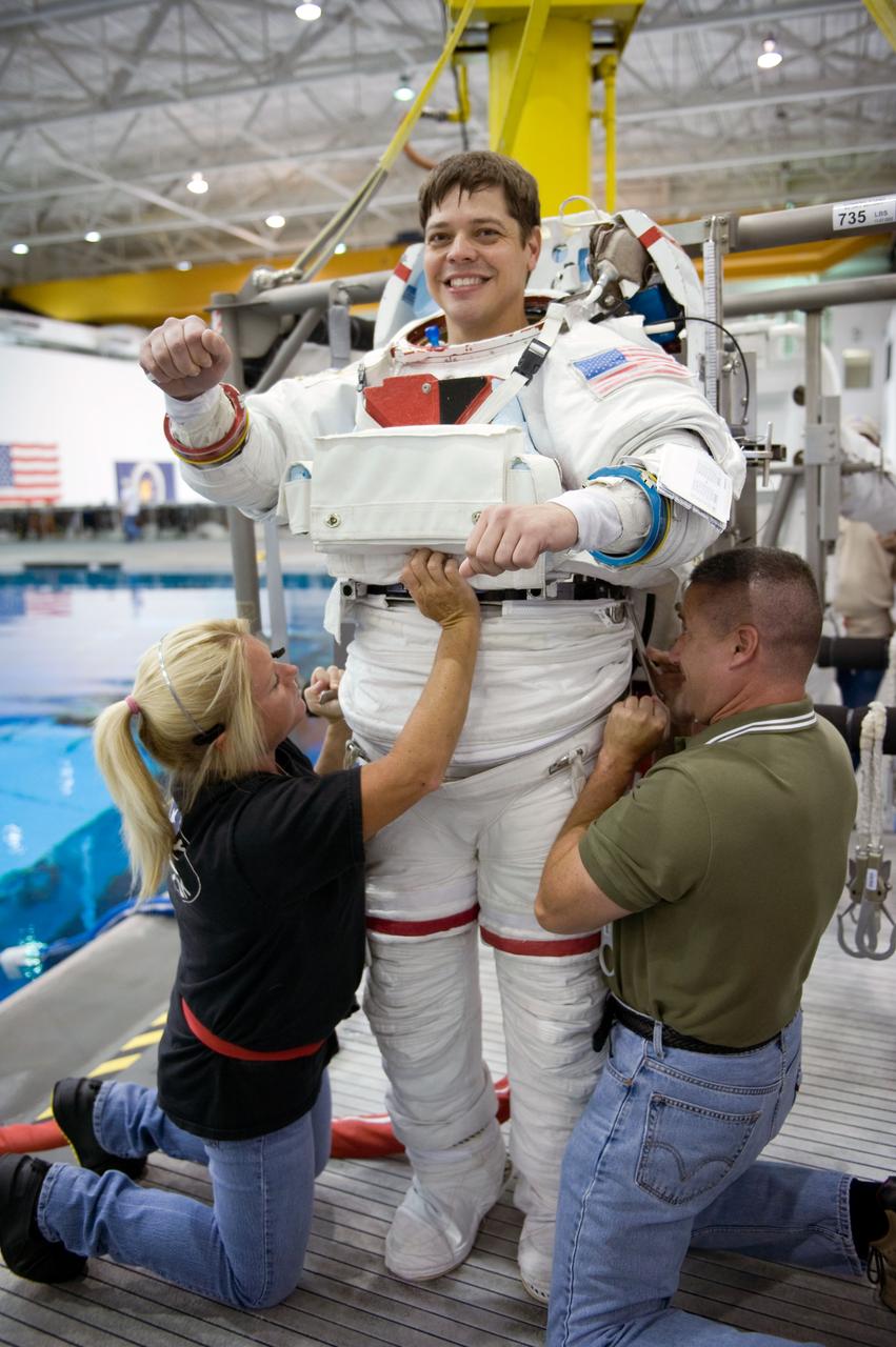 JSC2009-E-145700 (17 July 2009) --- Astronaut Robert Behnken, STS-130 mission specialist, gets help in the donning of a training version of his Extravehicular Mobility Unit (EMU) spacesuit in preparation for a spacewalk training session in the waters of the Neutral Buoyancy Laboratory (NBL) near NASA's Johnson Space Center.